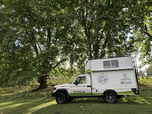 Box van parked in front of trees