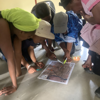 Photo of people gathered around looking and pointing at a map