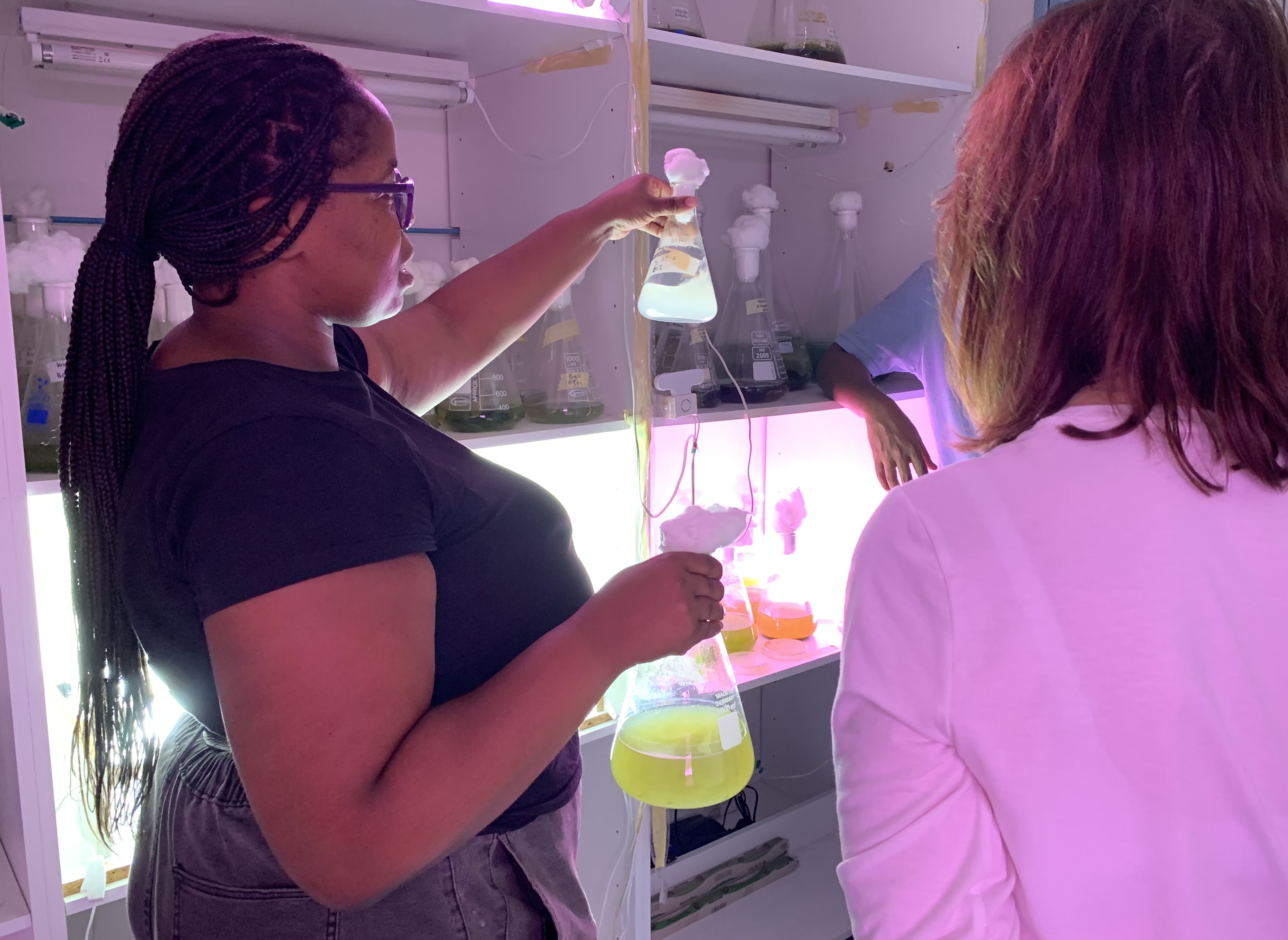 Woman holding triangular laboratory beaker with pale green liquid in laboratory setting