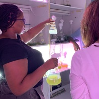 Woman holding triangular laboratory beaker with pale green liquid in laboratory setting