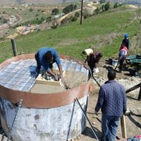 People building a concrete water tank in a rural setting